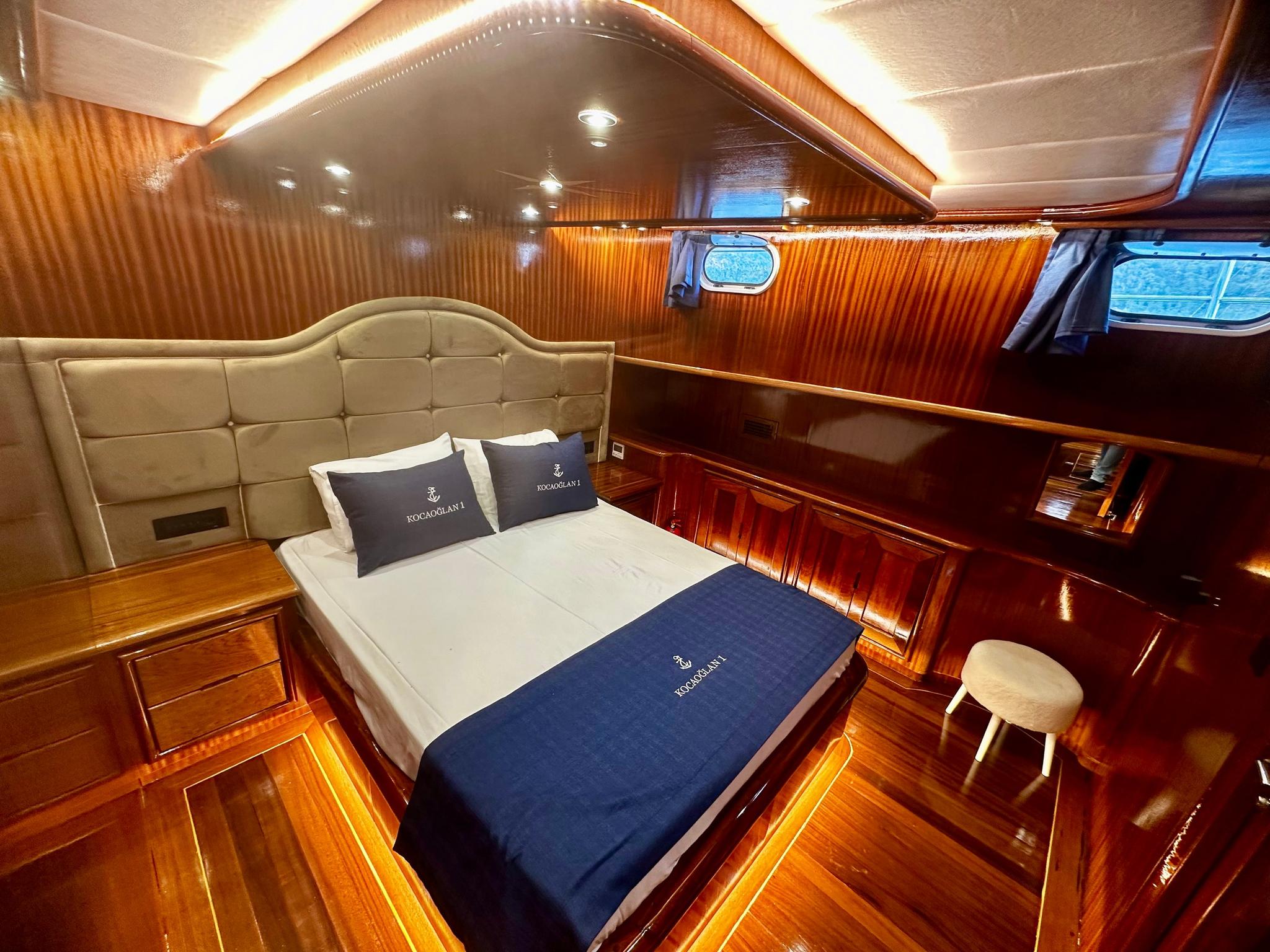 yacht guest cabin featuring double bed with cream upholstered headboard and rich wood paneling