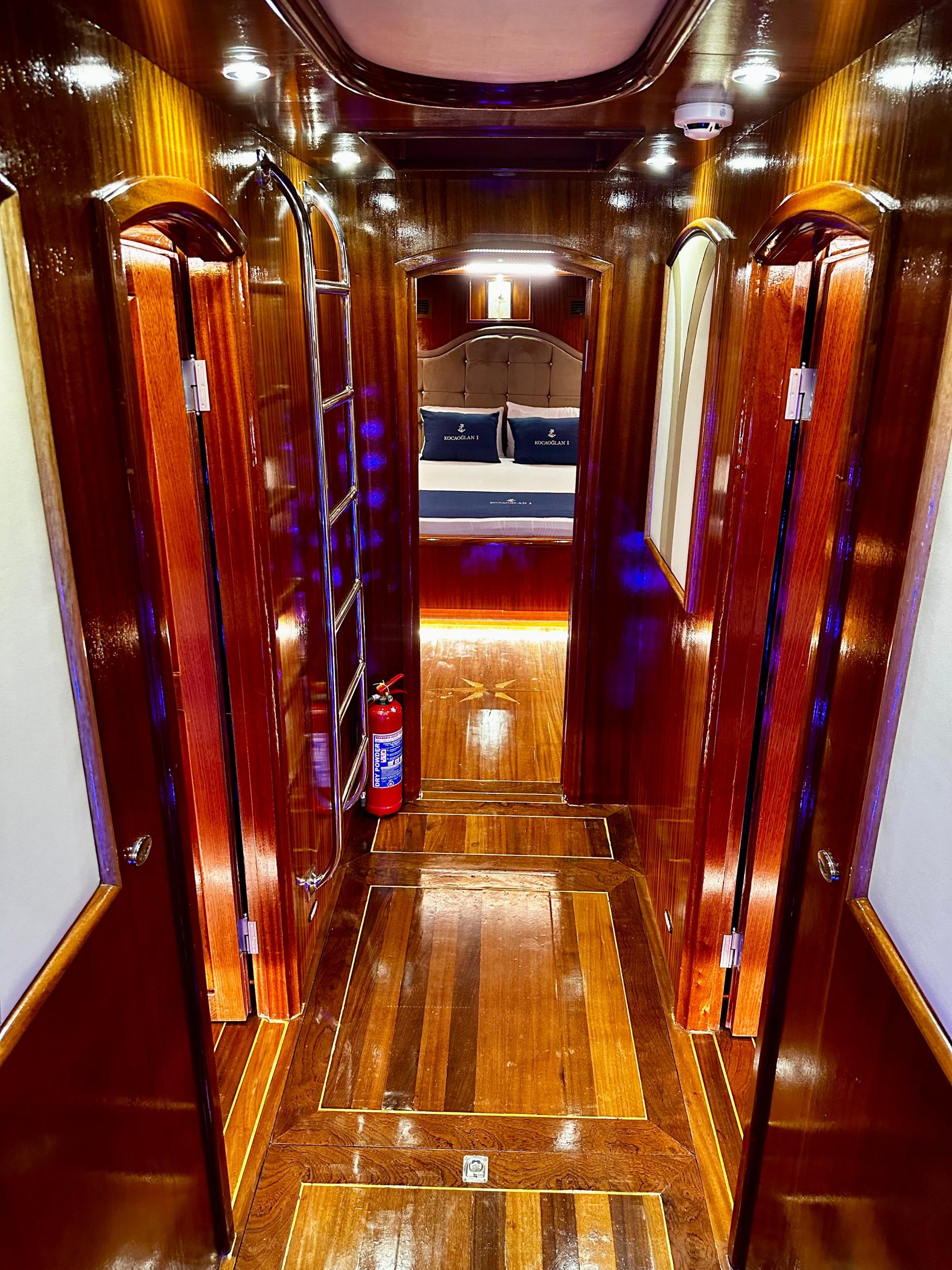 yacht interior companionway with polished wood stairs leading to cabin with double bed