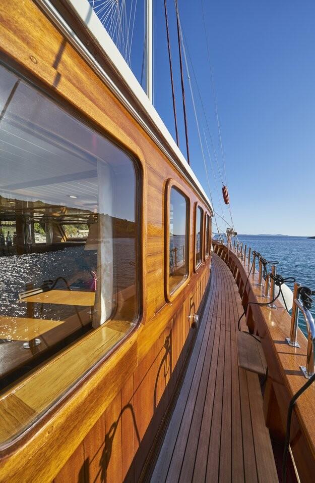 Traditional wooden gulet side deck with teak planking and cabin windows