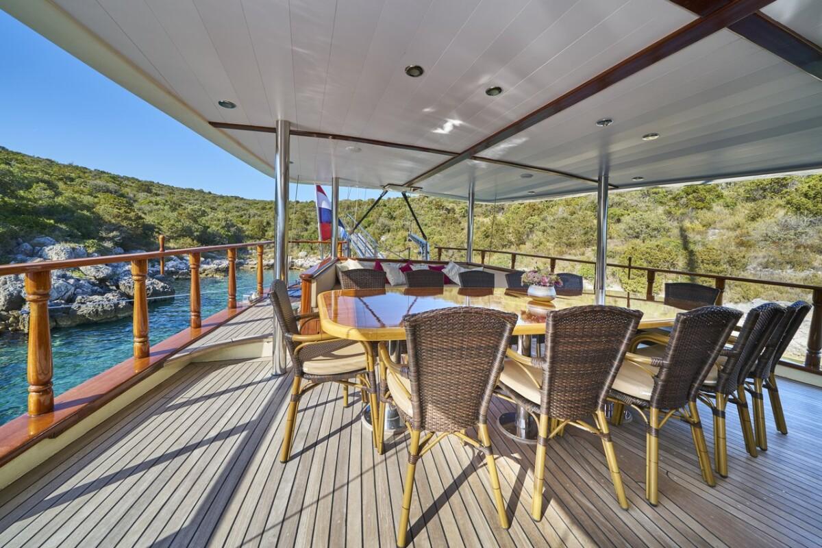 luxury yacht aft deck dining area with wicker chairs and hardtop canopy