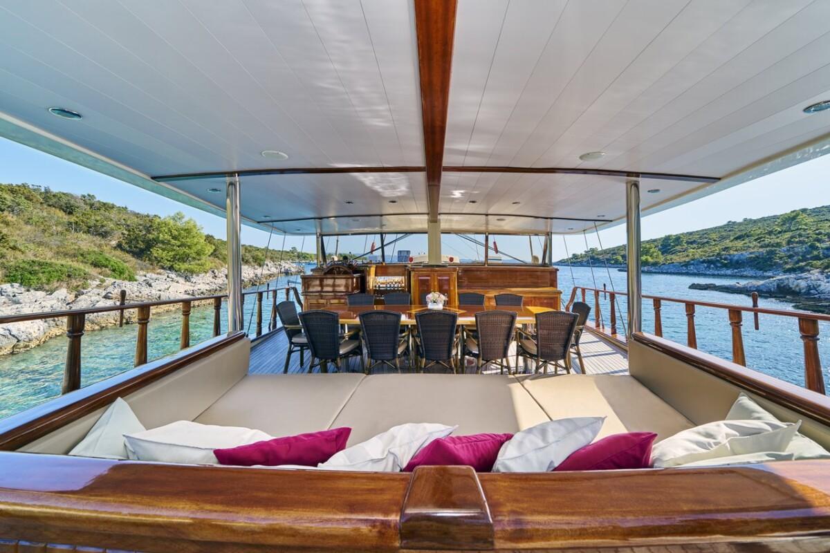luxury gulet aft deck with magenta pillows and dining area in Mediterranean cove