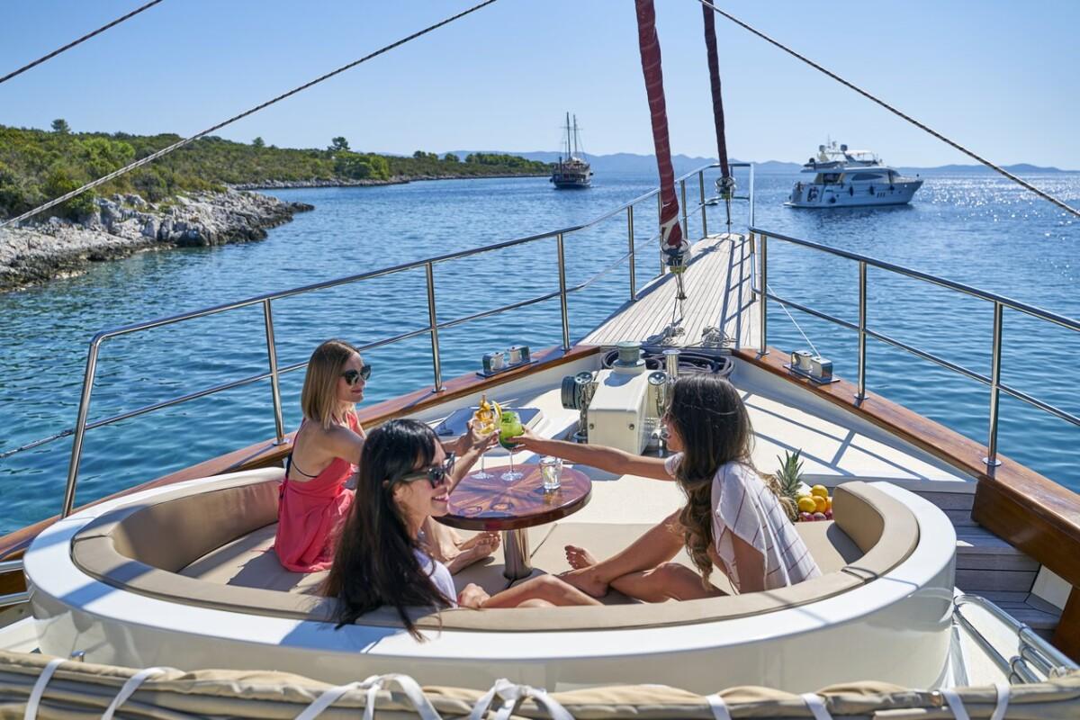 Three women relaxing in circular bow seating area of luxury yacht