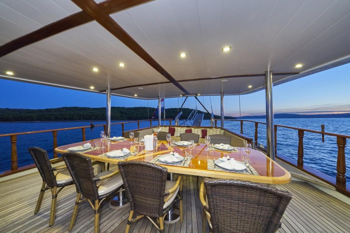 luxury gulet aft deck dining area with formal table setting at twilight