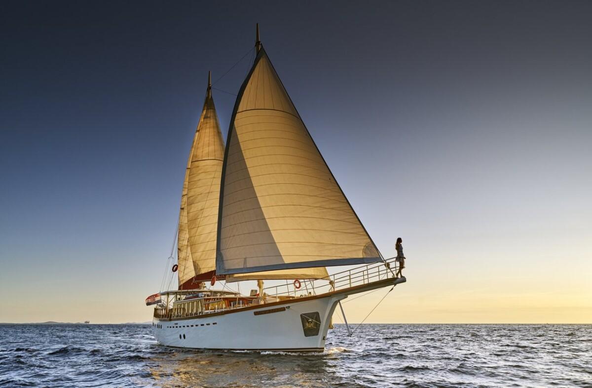 White gulet sailing yacht with cream triangular sails on open water