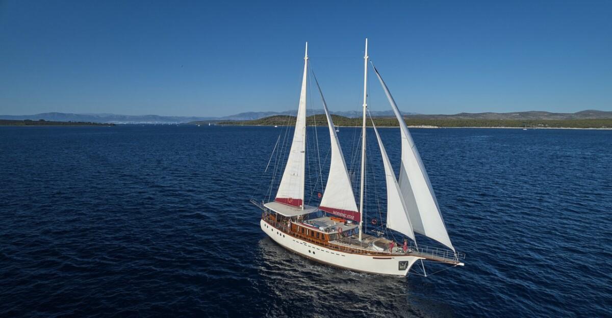 Traditional wooden gulet yacht sailing with white sails on blue Mediterranean waters