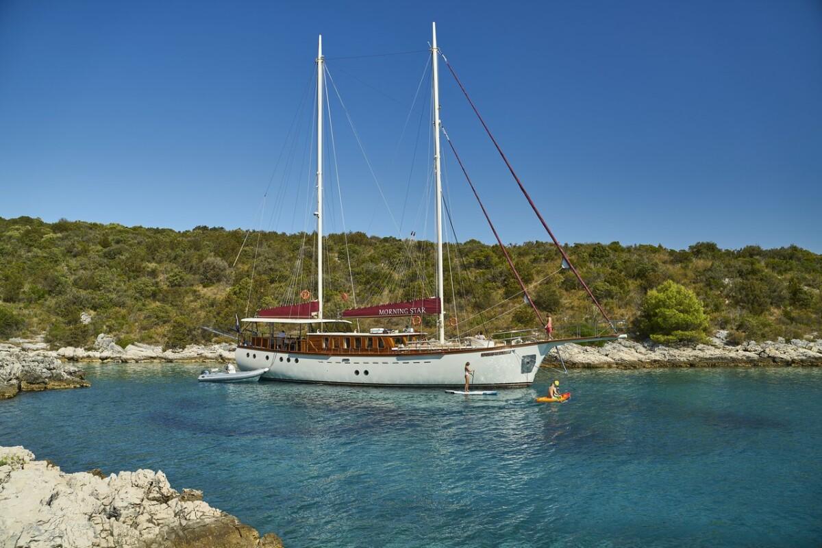 Morning Star gulet with burgundy awnings anchored in secluded turquoise cove