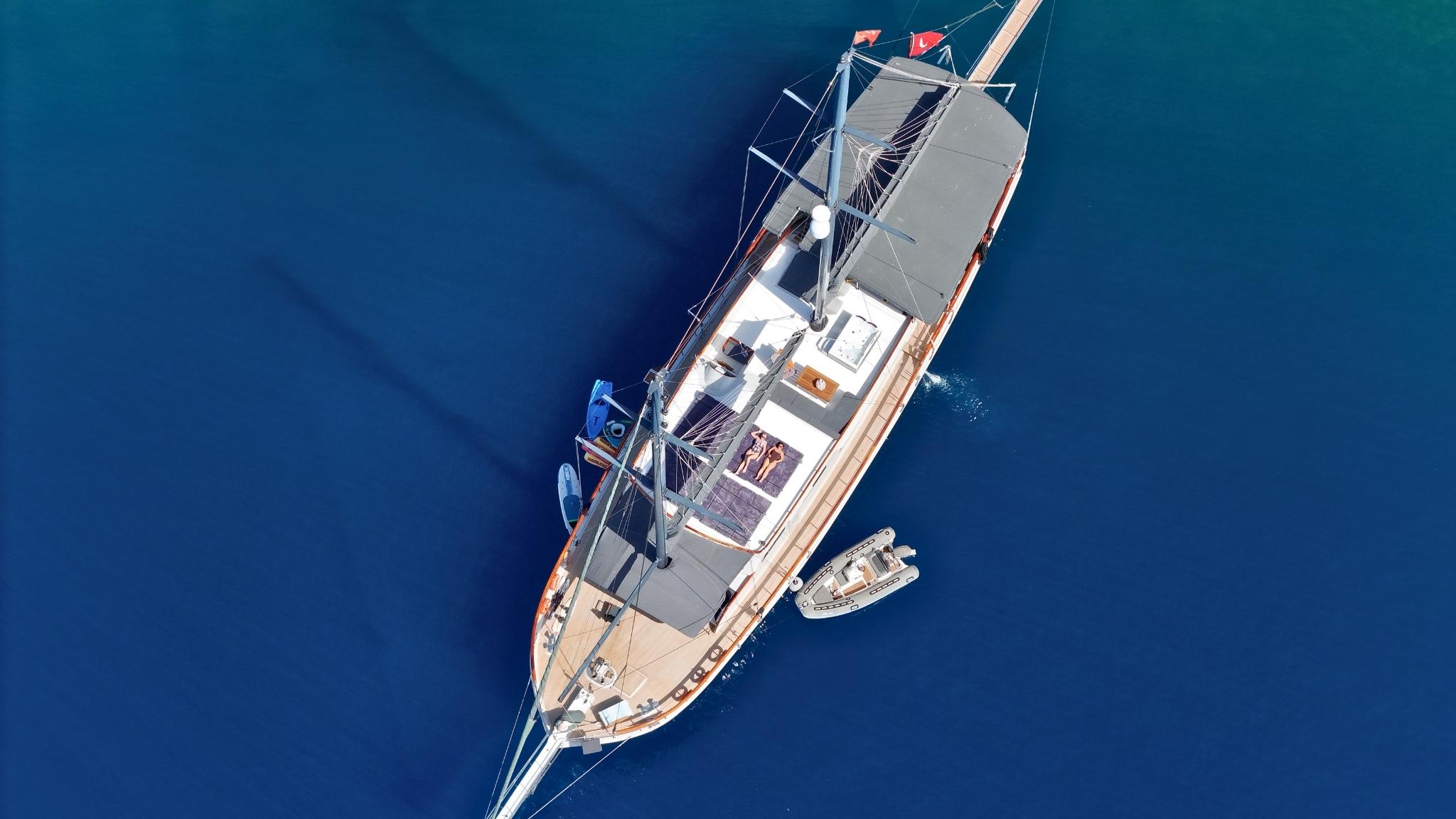 aerial view of luxury gulet yacht anchored in deep blue water with tender boat