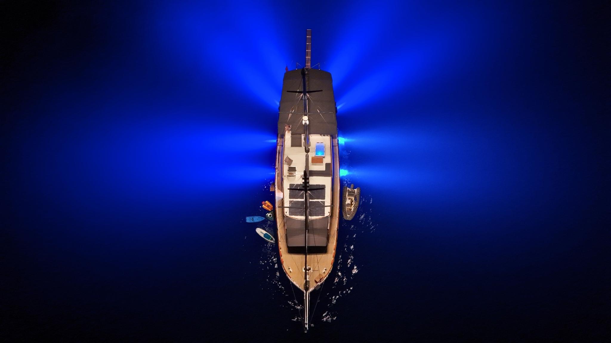 aerial drone view of luxury wooden gulet yacht anchored in deep blue waters