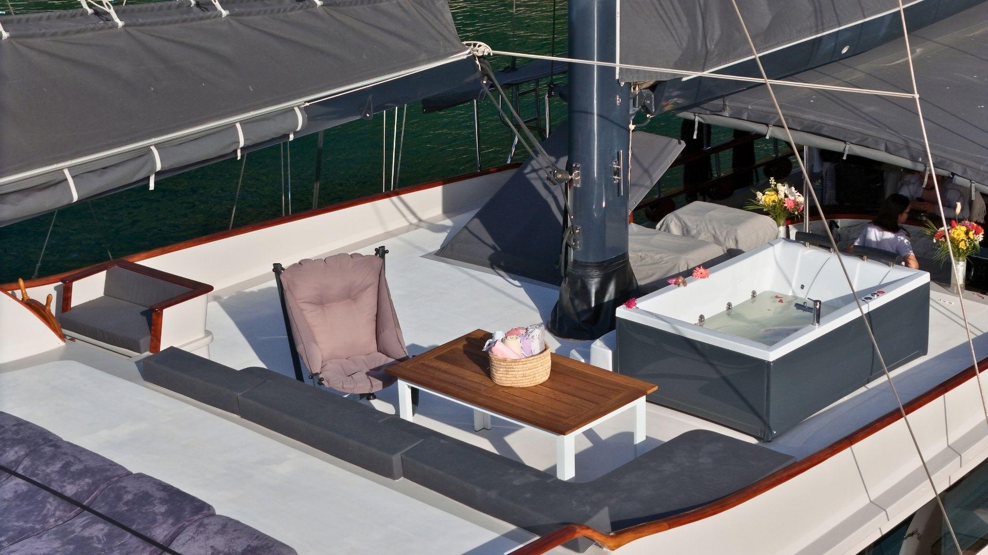 yacht deck jacuzzi with white rectangular tub, cushioned seating and wooden coffee table