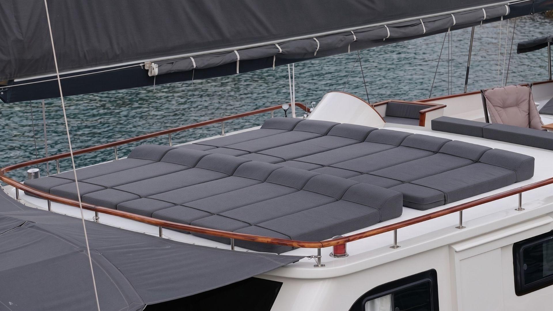bow sun deck featuring large gray quilted sunbathing mattress with yacht railings