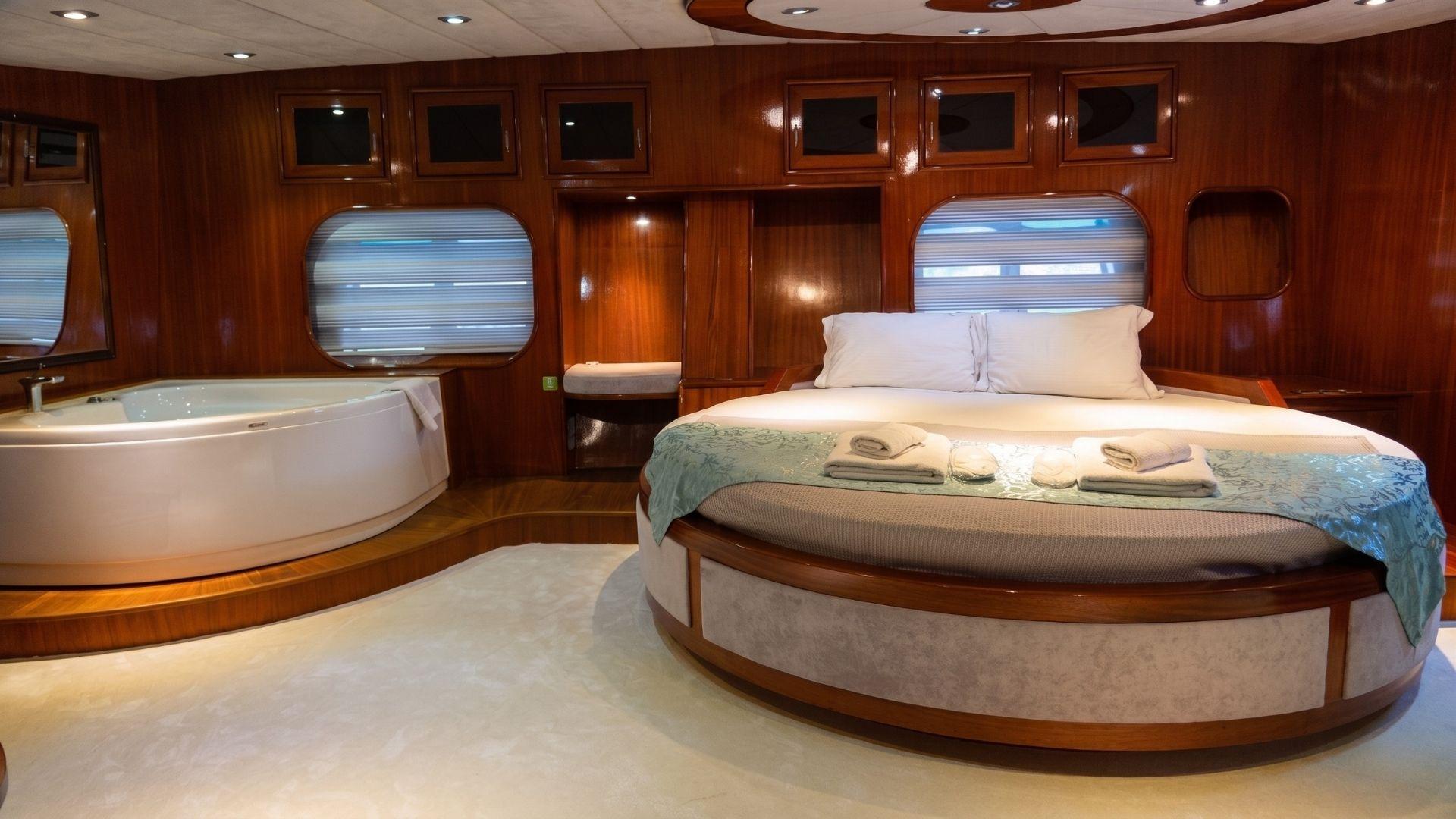 luxury yacht master cabin featuring circular bed and white corner jacuzzi tub