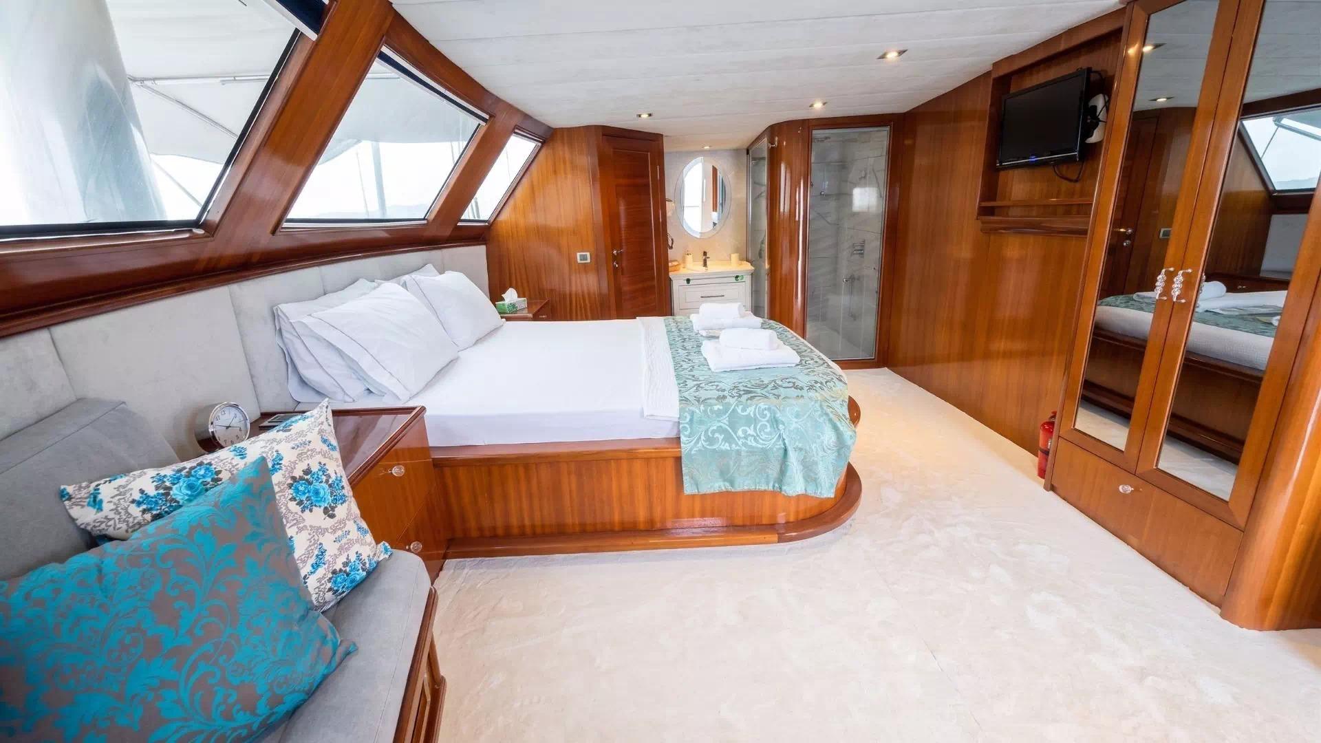 spacious yacht cabin featuring double bed with white linens, wood paneling, en-suite bathroom, and panoramic windows