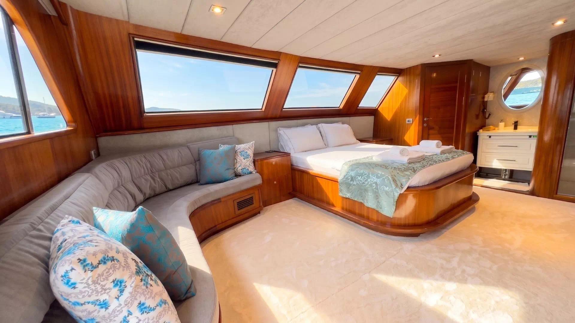 luxury yacht master cabin featuring king bed, curved seating area, and panoramic hull windows