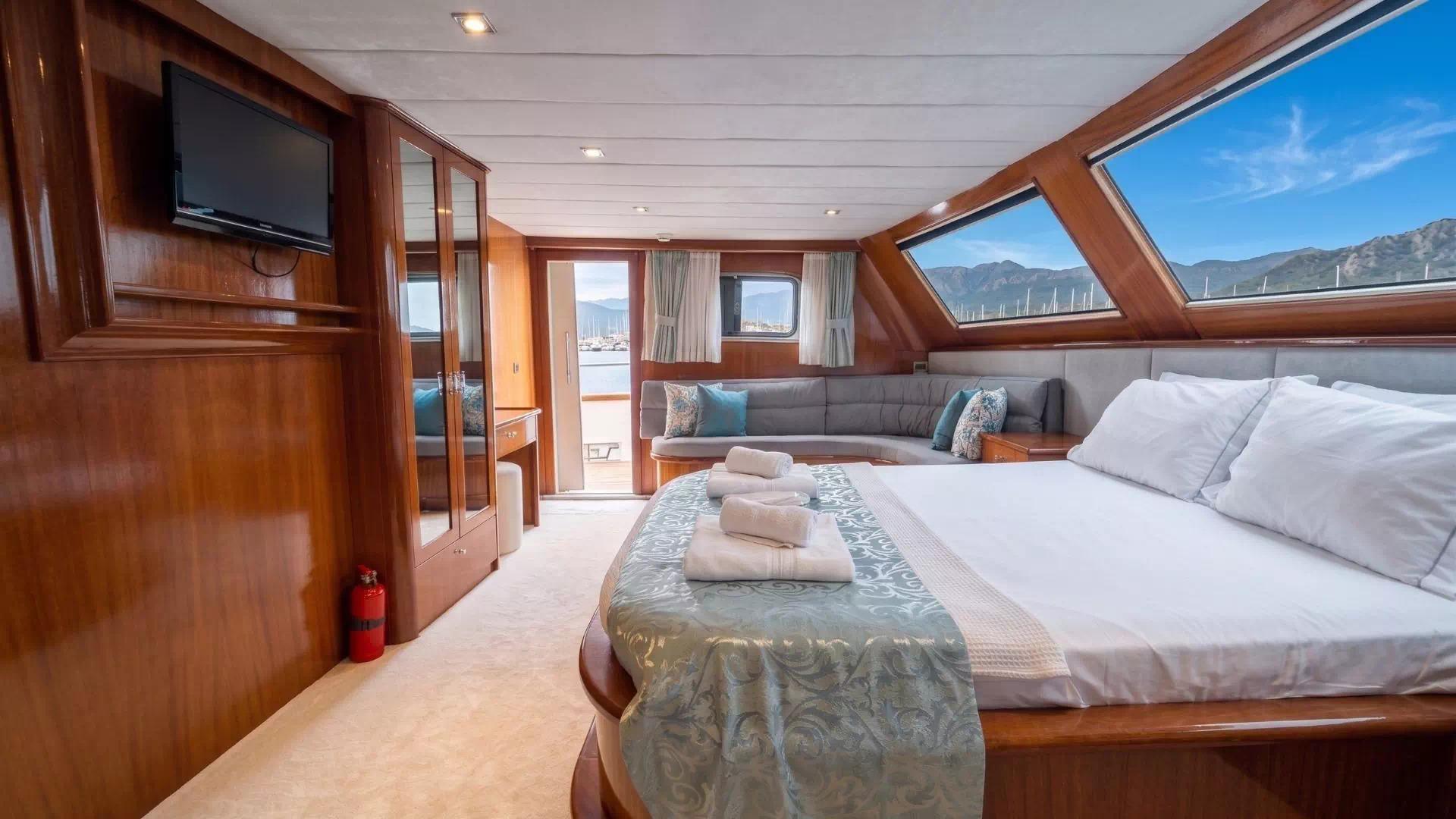 luxury yacht master cabin with king bed, panoramic windows, seating area and entertainment system