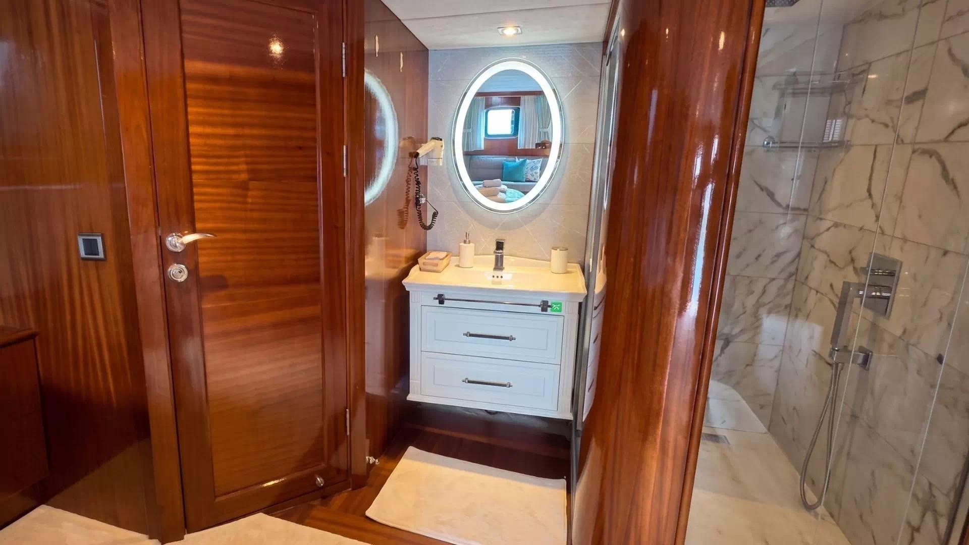 luxury yacht bathroom featuring white vanity unit, oval porthole mirror, and marble shower enclosure