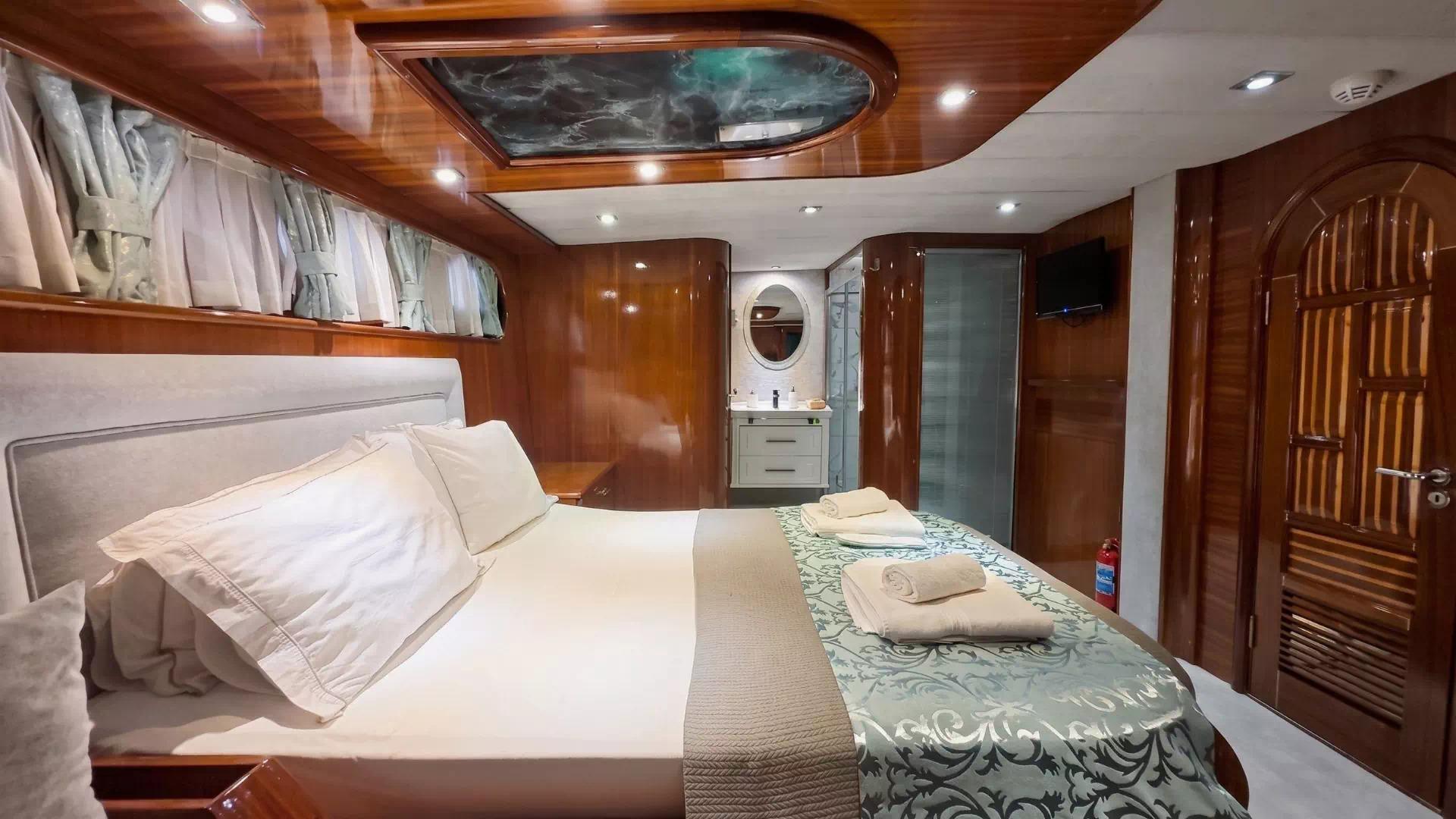 yacht guest cabin with double bed, overhead skylight, built-in wardrobes and ensuite bathroom