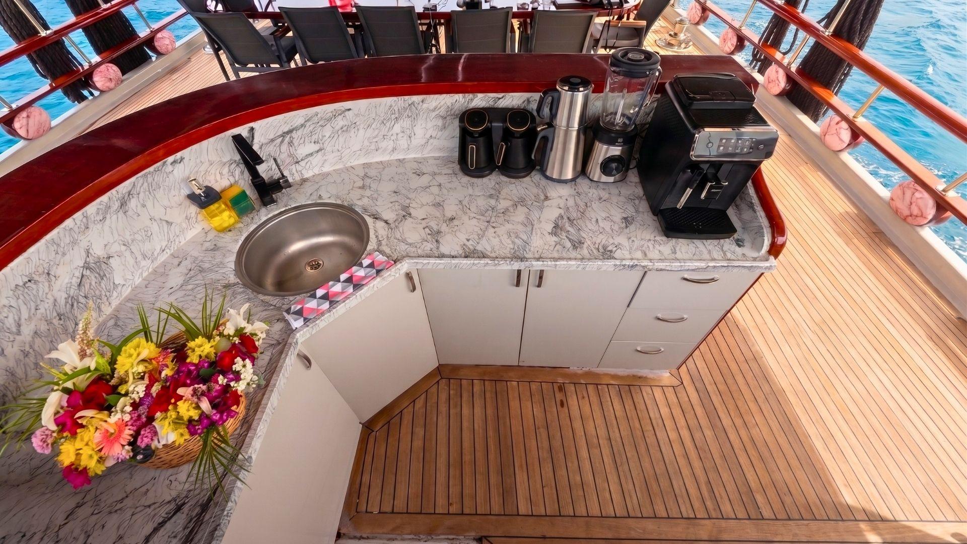 Gulet deck bar with marble countertop, round stainless sink, espresso machine, blender, coffee appliances and fresh flower basket