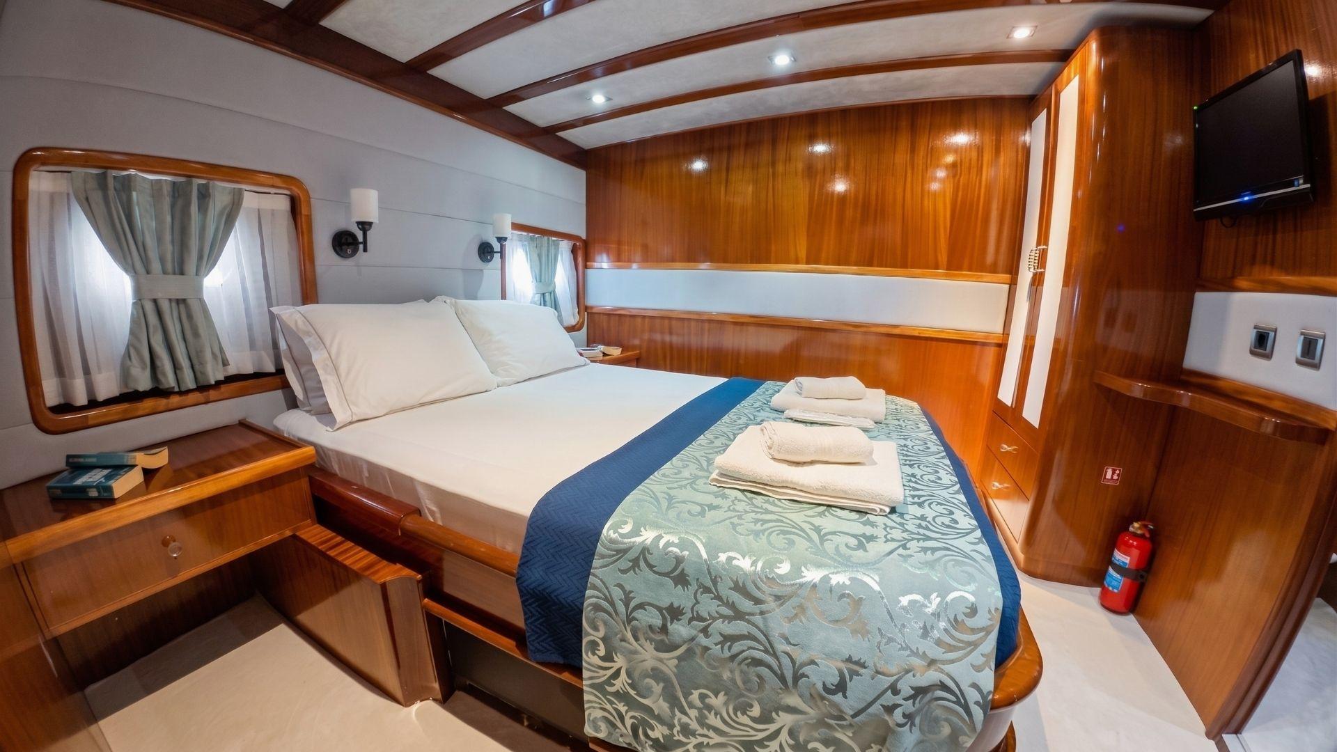 Gulet double cabin with king bed, ornate bedrunner, walnut panelling and flat-screen TV