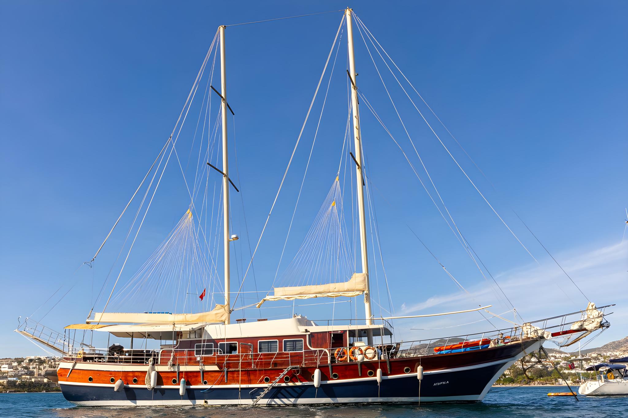 Traditional wooden gulet with two masts and rigging moored in Mediterranean harbor