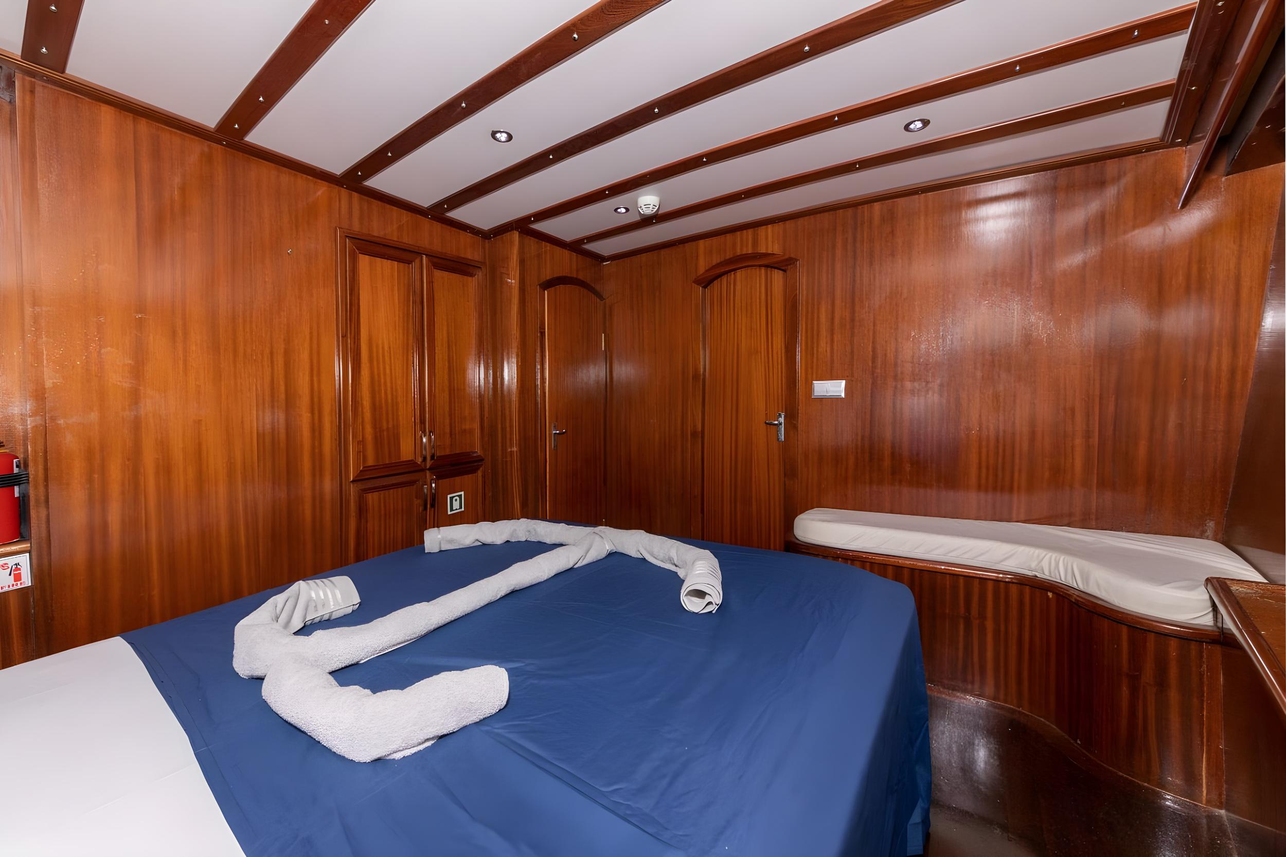 yacht guest cabin featuring double bed with blue bedding and white towels arranged decoratively