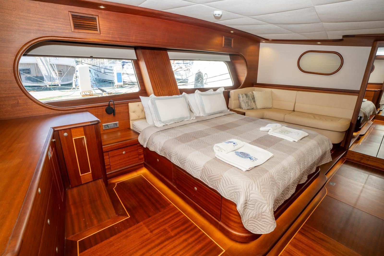 luxury yacht master cabin with king bed, panoramic windows, cream upholstery and rich wood finishes