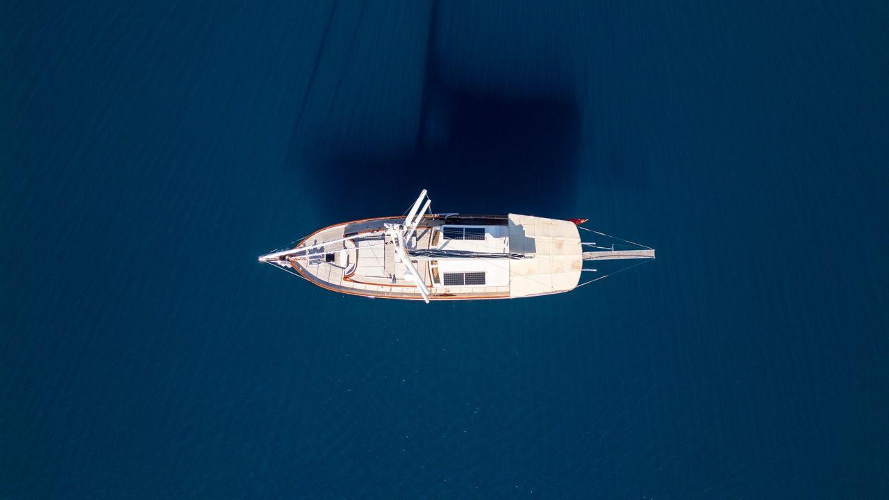 aerial view of white sailing yacht with mast anchored in deep blue Mediterranean waters