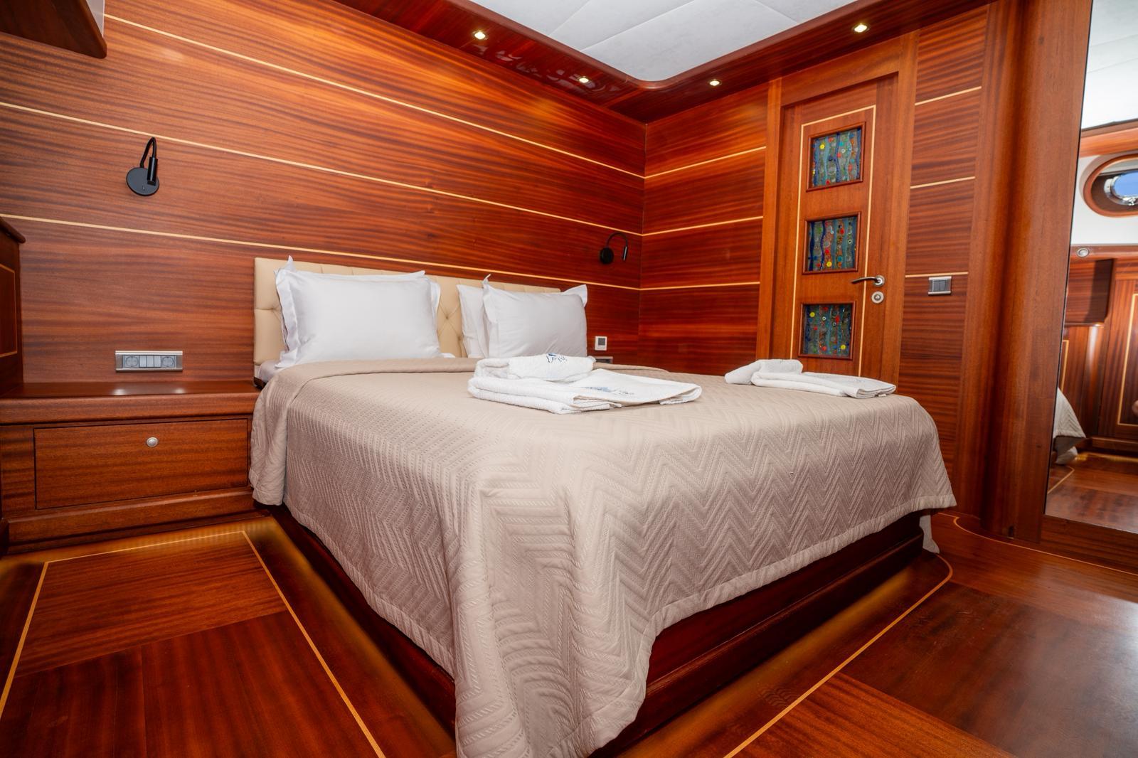 yacht guest cabin featuring double bed with beige bedding and rich wood paneled walls