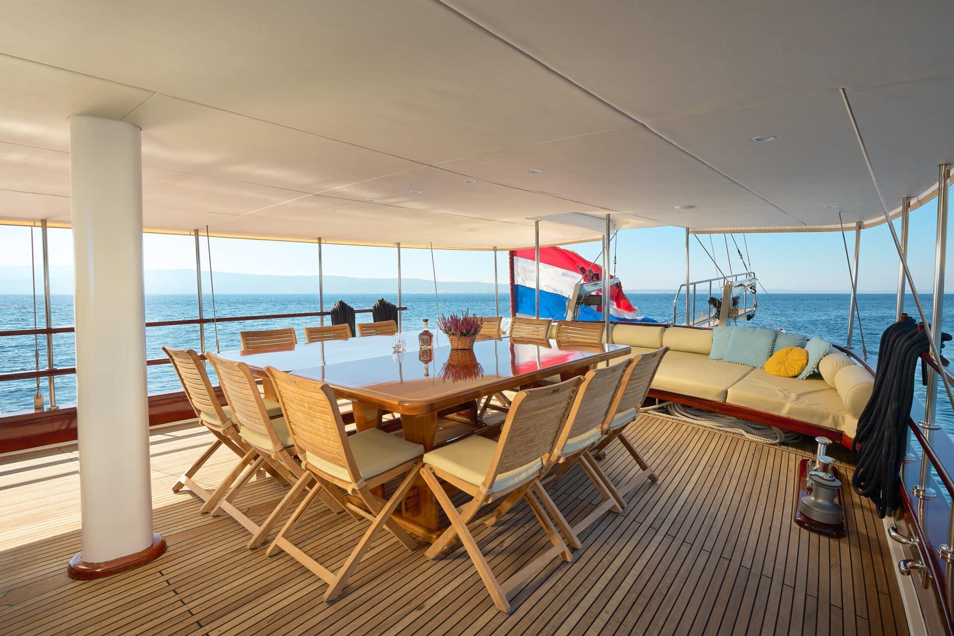 covered aft deck with teak dining table, folding chairs, and built-in seating area