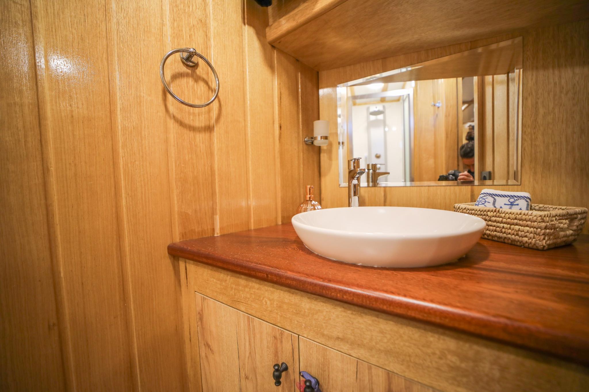yacht bathroom featuring white ceramic vessel sink on wooden vanity with mirror