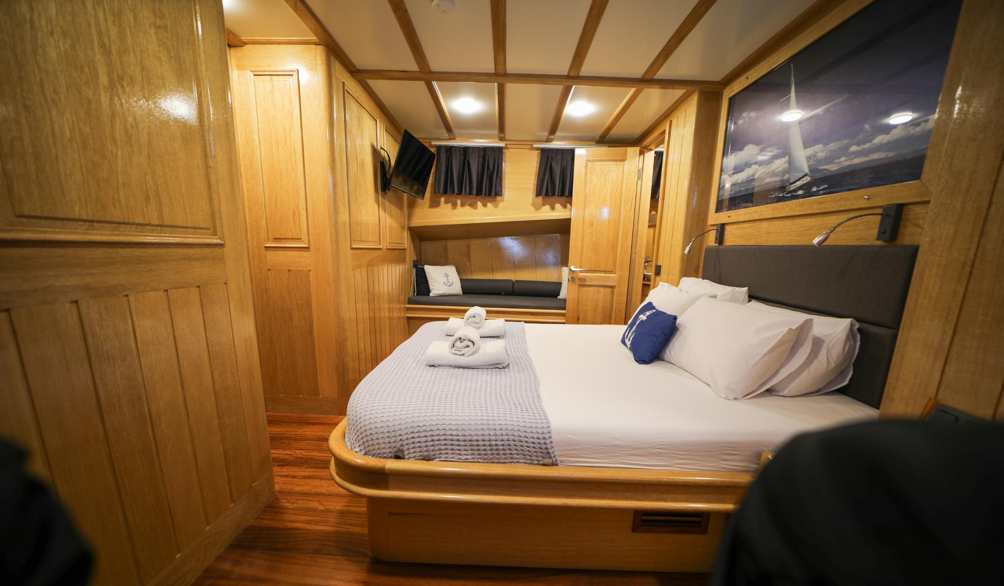 yacht guest cabin featuring double bed with white linens, extensive wooden cabinetry and storage
