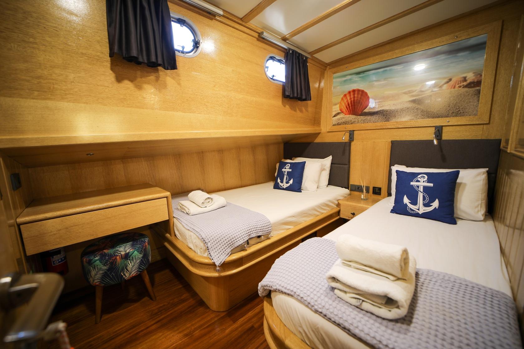 yacht twin cabin featuring two single beds with nautical blue pillows and wooden paneling