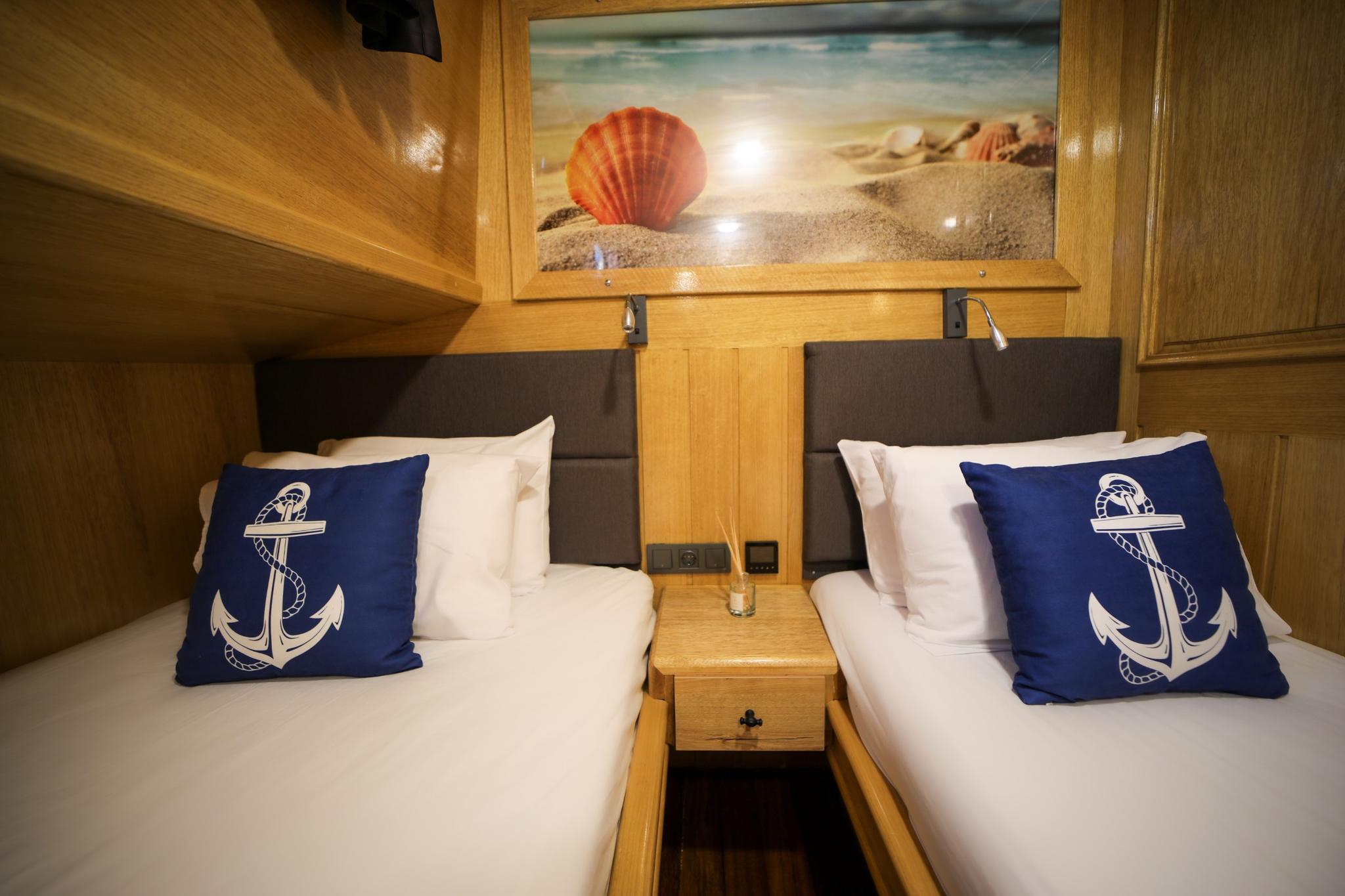 yacht twin cabin with two single beds, navy anchor pillows, and beach shell artwork