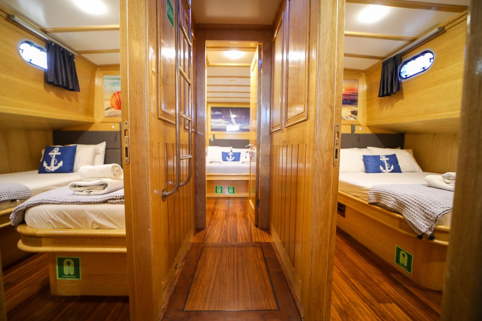 yacht guest cabin featuring twin bunk beds with anchor pillows and en-suite bathroom