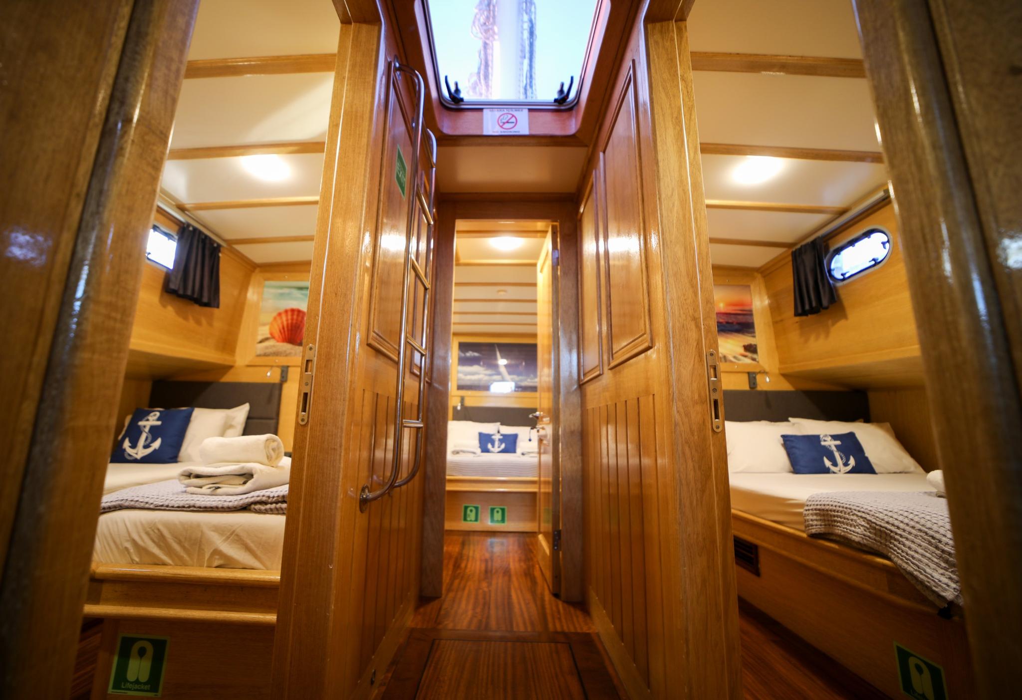yacht guest cabin interior showing bunk beds on both sides with nautical blue anchor pillows