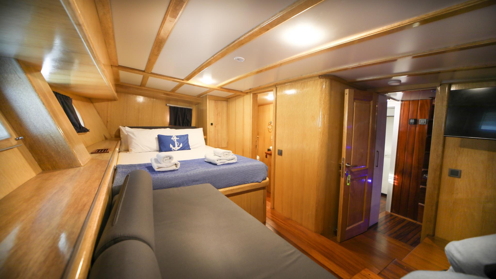 yacht guest cabin featuring double bed with blue nautical bedding and exposed wooden beams