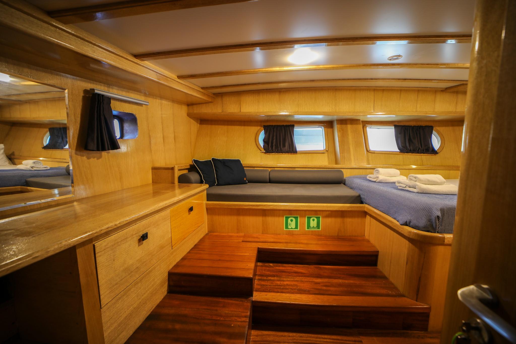 yacht cabin with twin beds, wooden paneling, portholes and built-in storage