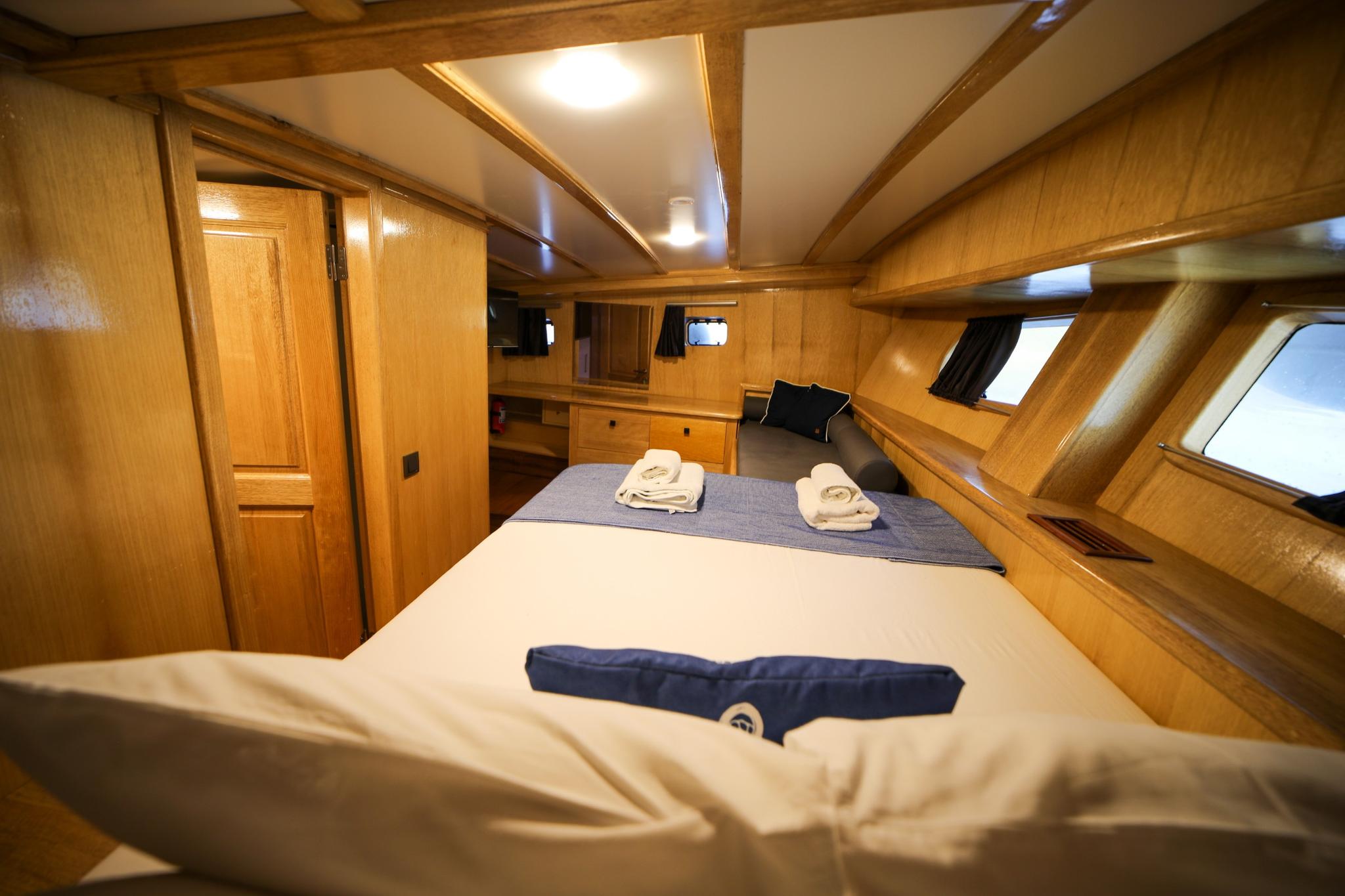 yacht cabin interior featuring double bed with white linens, extensive wood paneling and storage
