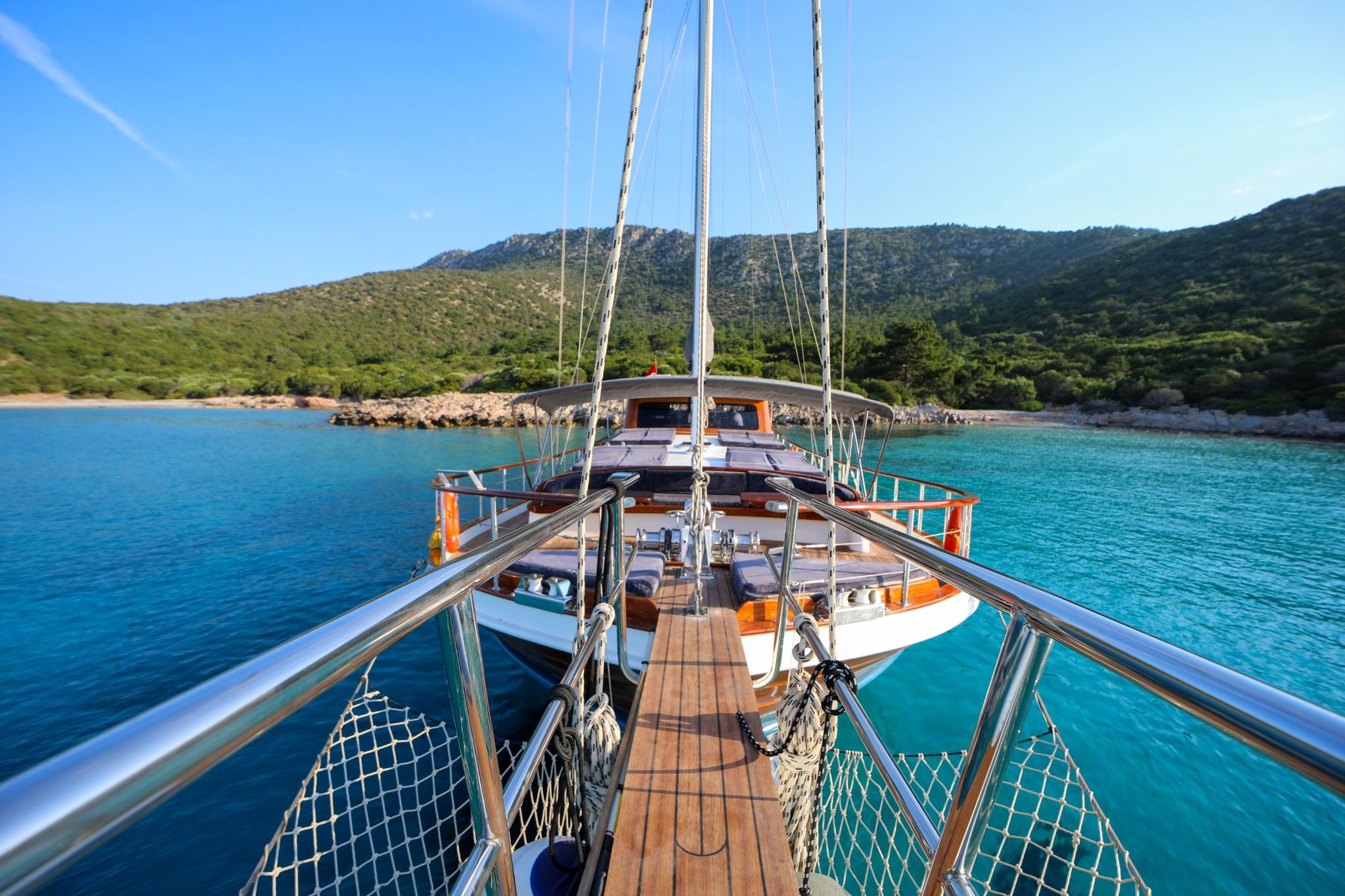 gulet bow deck with teak planking, white cushioned seating areas, and stainless steel railings