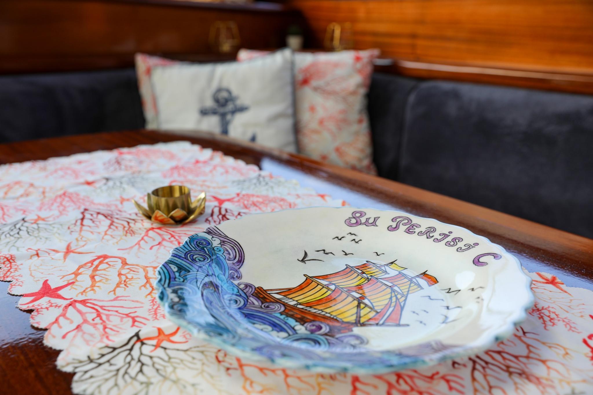 decorative ceramic plate featuring colorful sailing ship design on yacht dining table