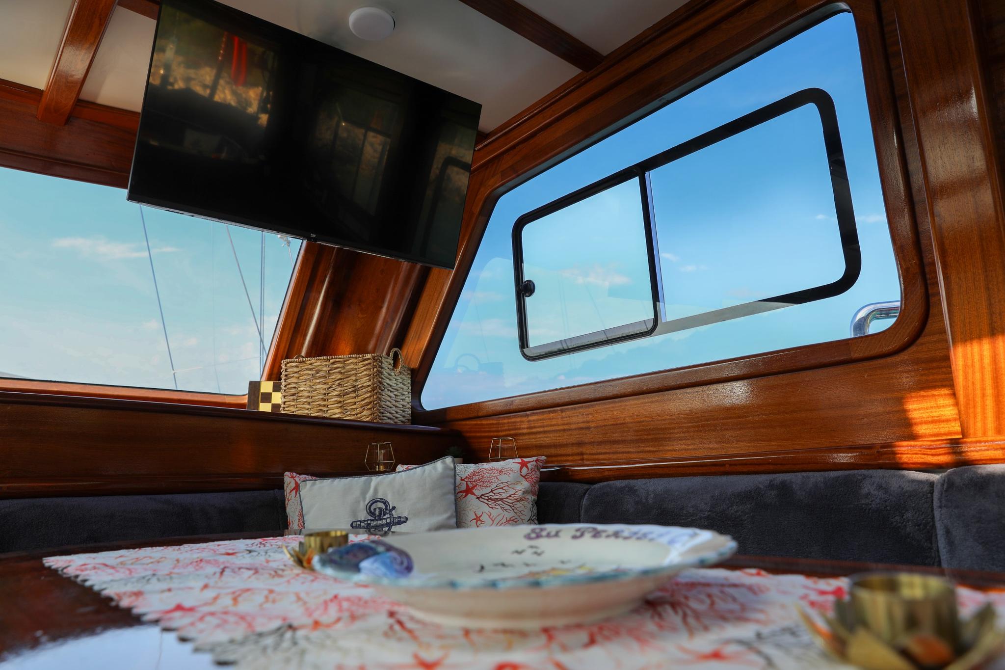 yacht cinema room with wall-mounted TV screen and comfortable seating with nautical pillows