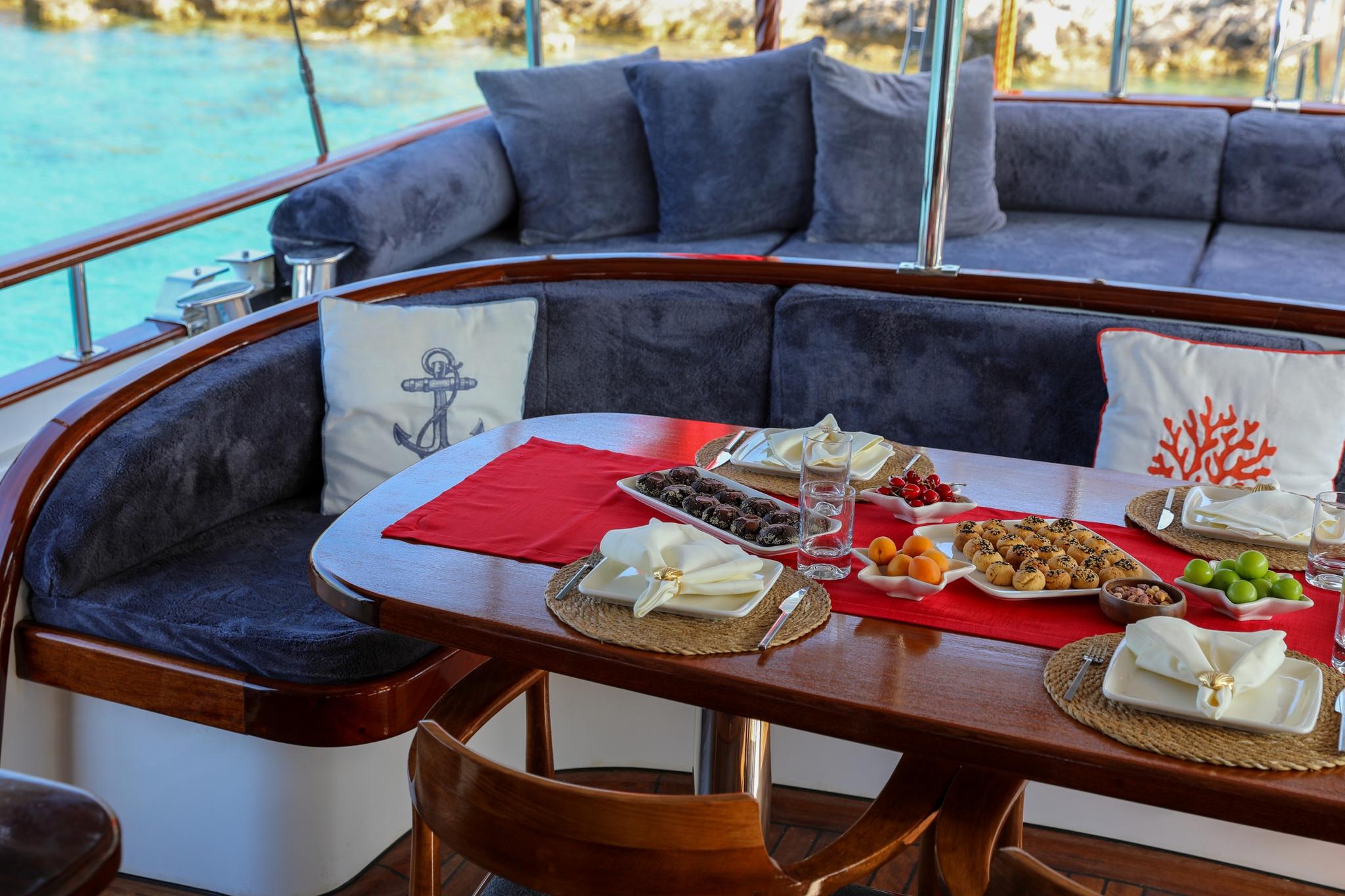 yacht dining table with Mediterranean appetizers, cocktails, and red table runner on deck