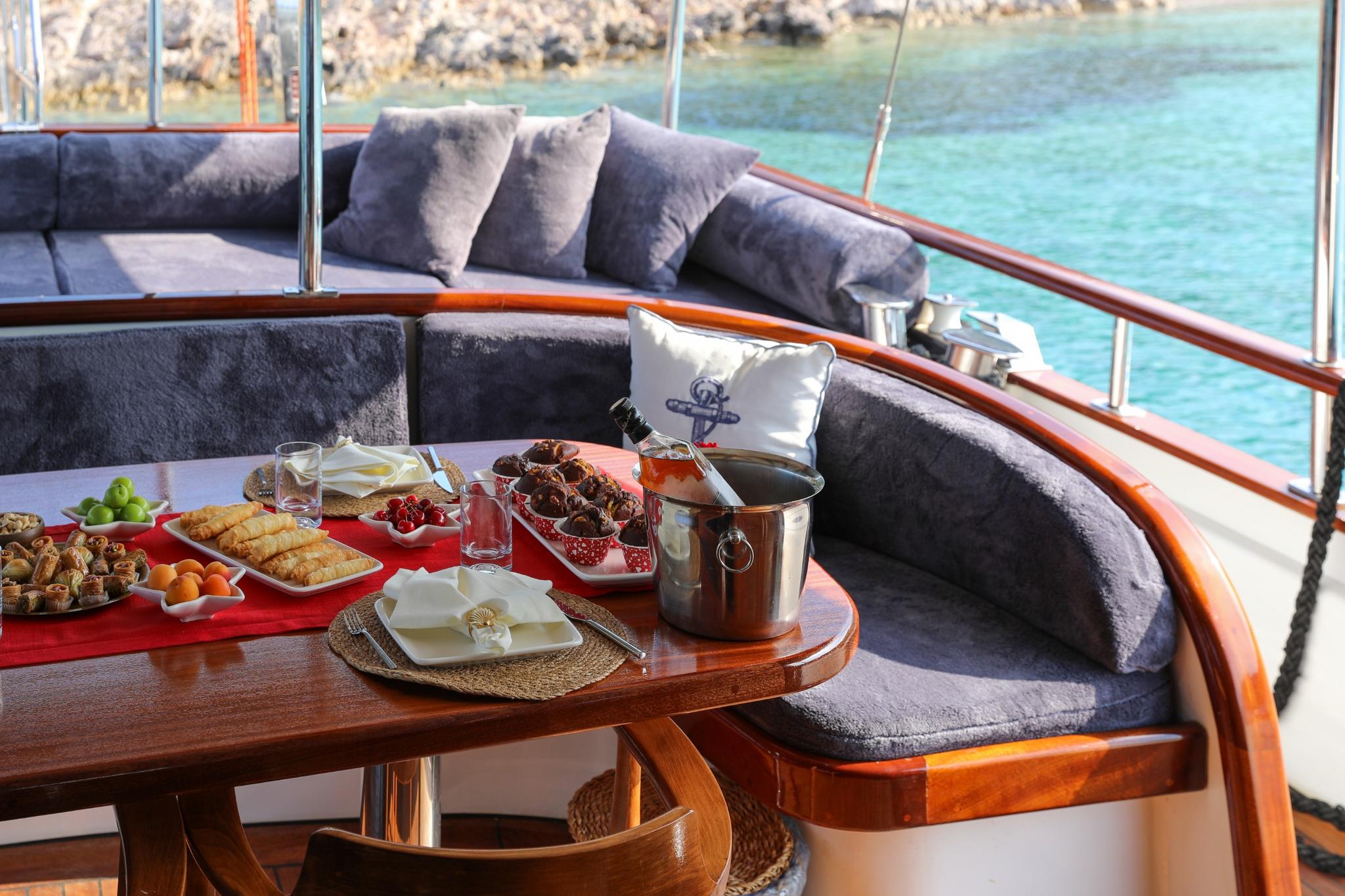 yacht dining table with champagne bucket, appetizers, and food spread in curved seating area