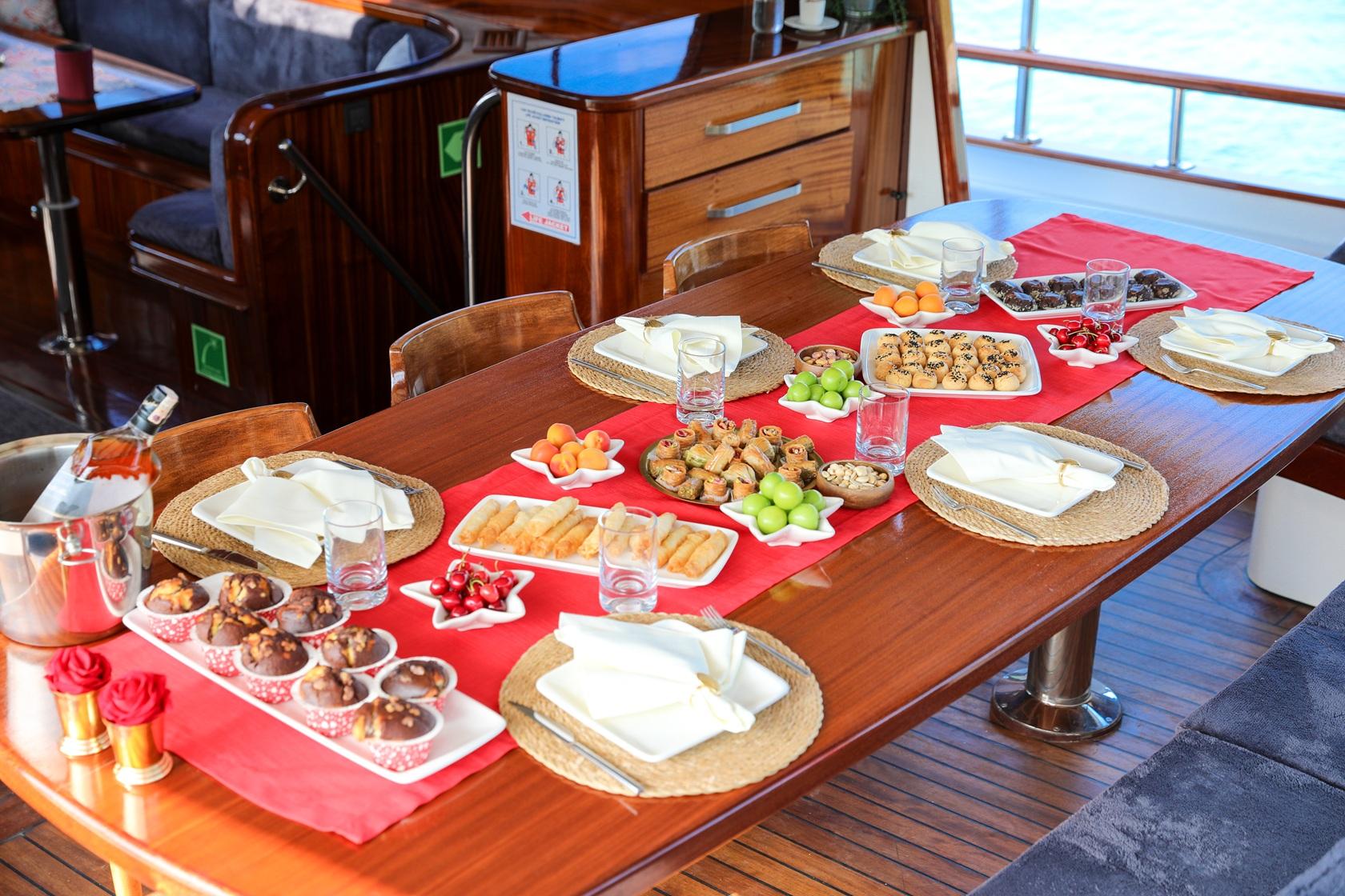 yacht dining table with red runner, wicker placemats, appetizer platters, glasses and white napkins