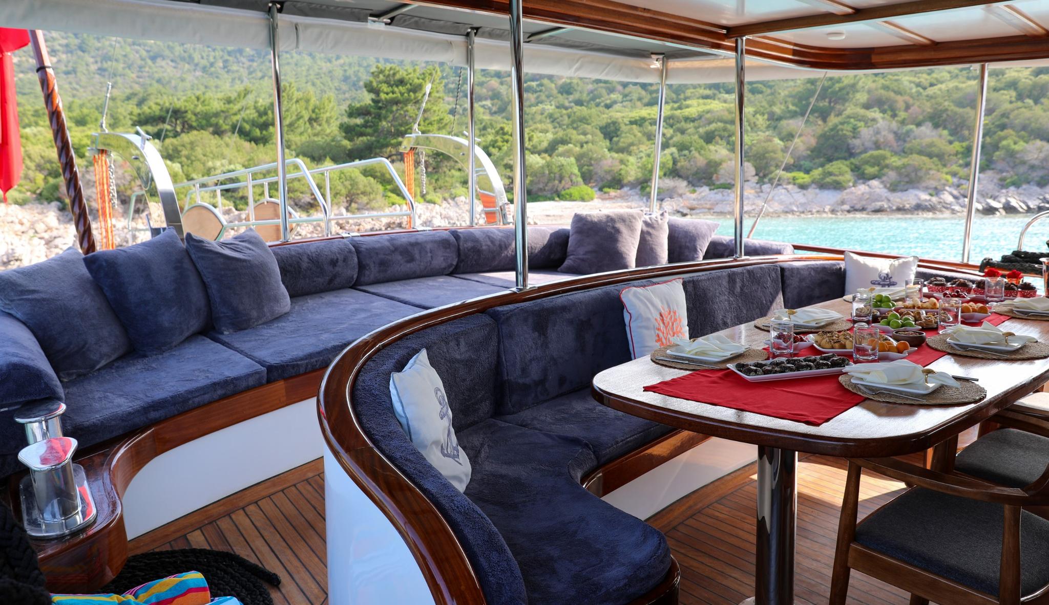 yacht aft deck dining area with curved seating, table set with appetizers and refreshments