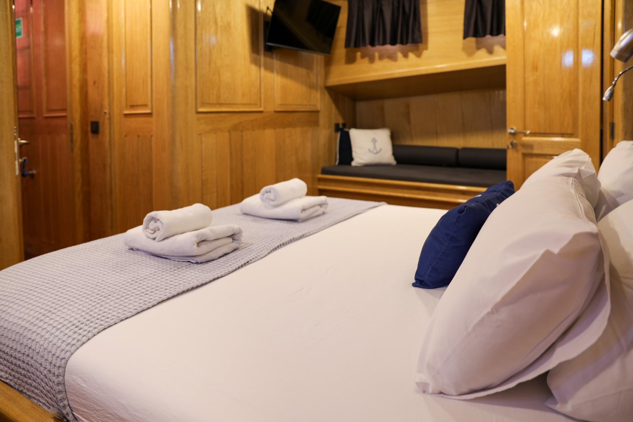 yacht guest cabin featuring double bed with white linens and built-in seating nook