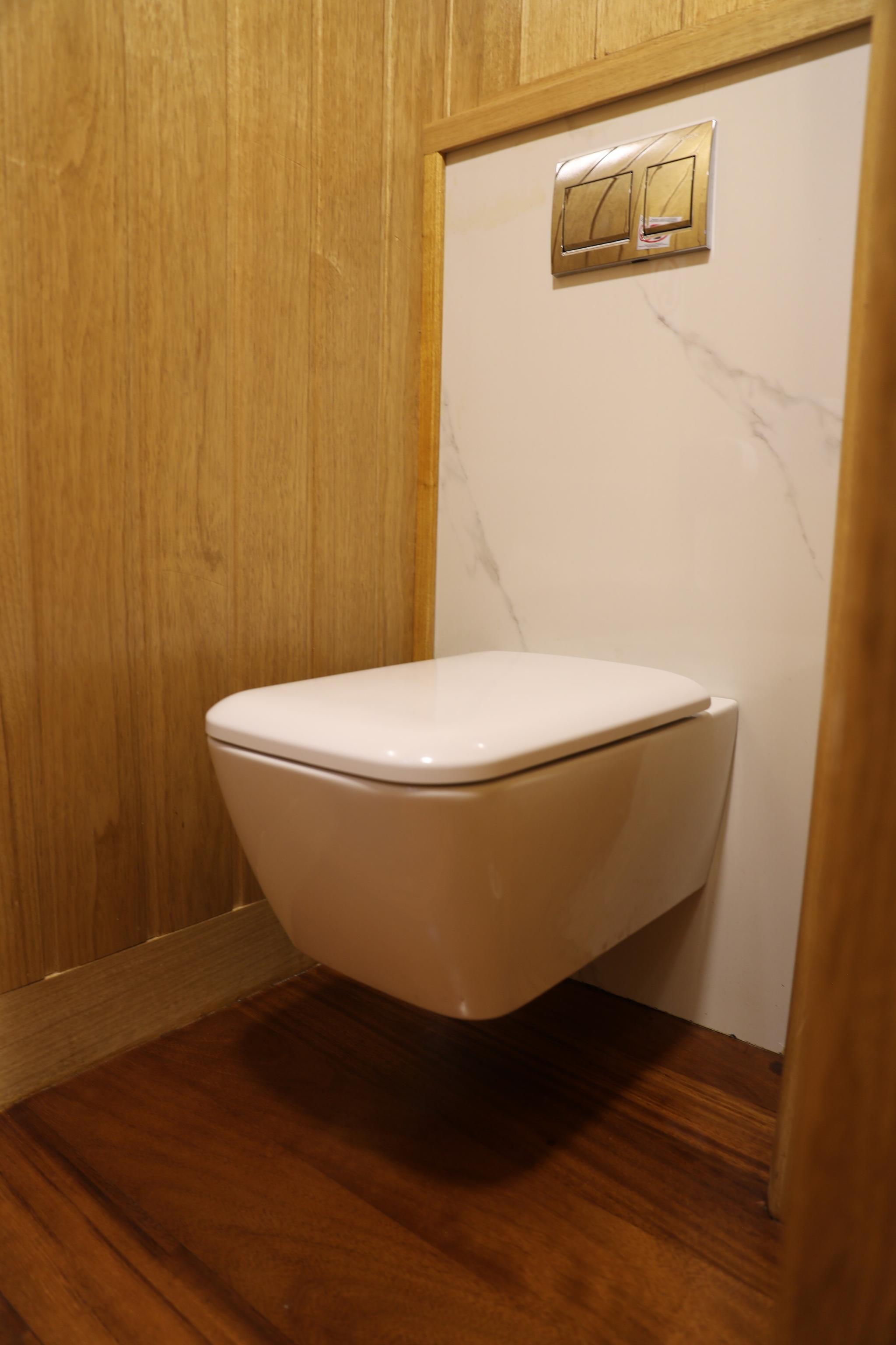 yacht bathroom featuring wall-mounted toilet with dual flush buttons and wood paneling