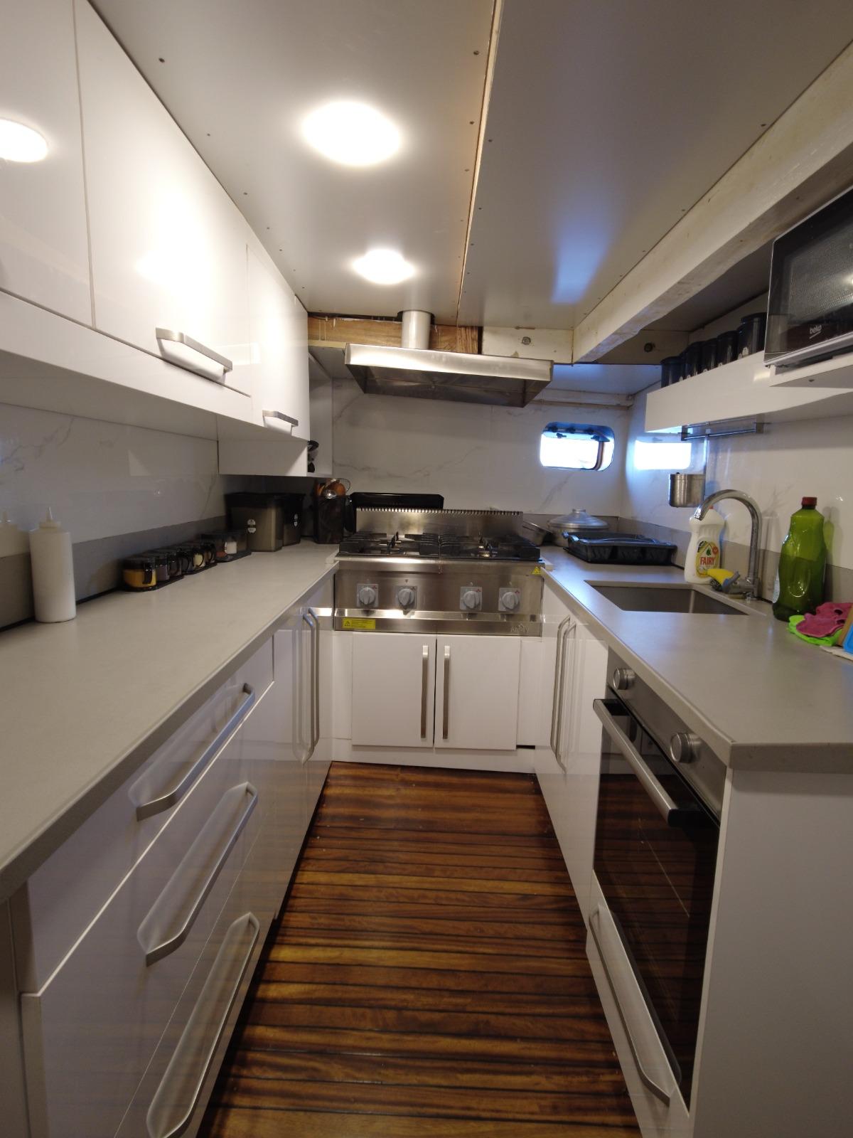 modern yacht galley with white cabinets, stainless steel appliances and teak flooring