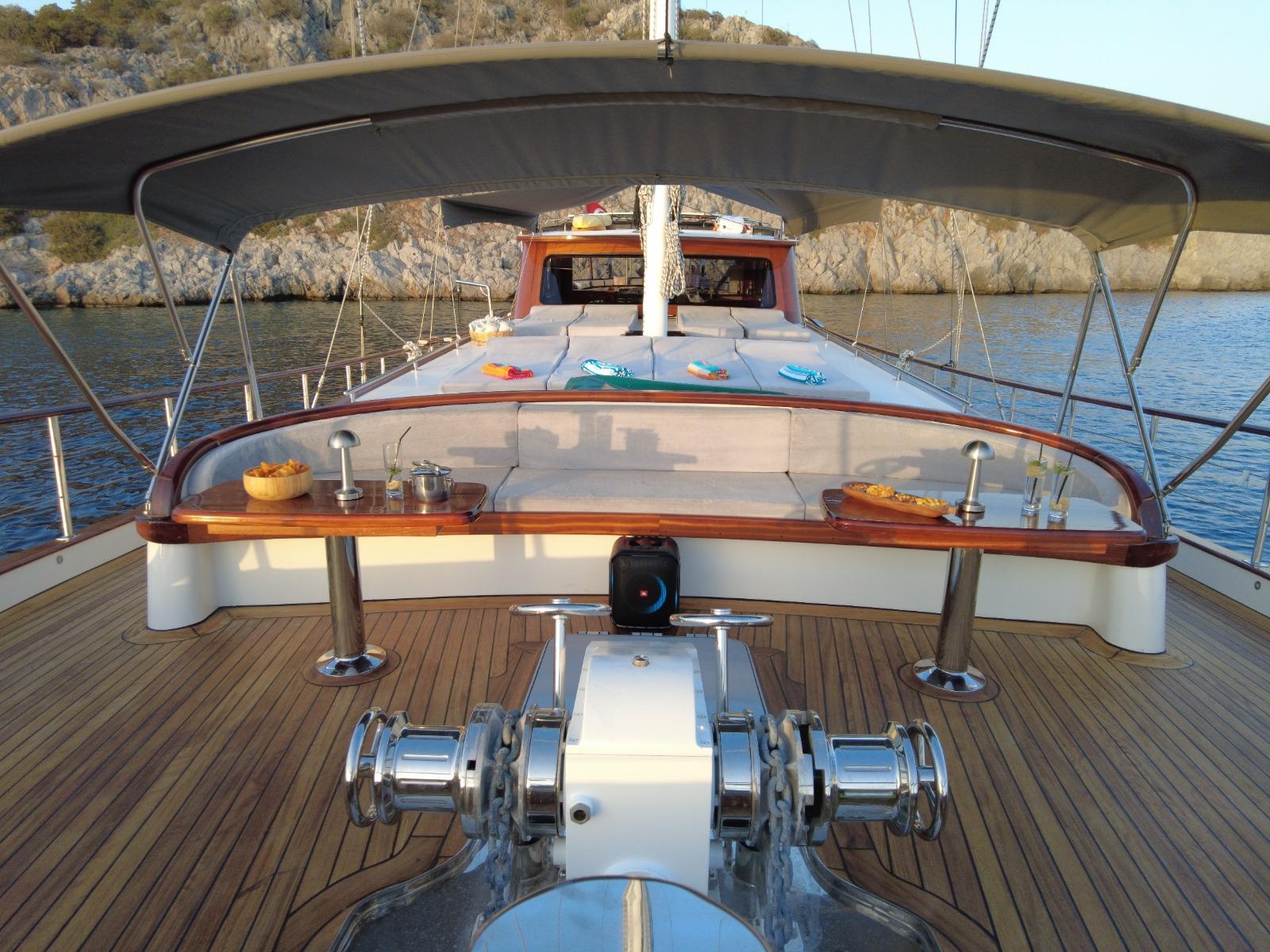 yacht aft deck with curved bench seating, polished wood table, and windlass machinery