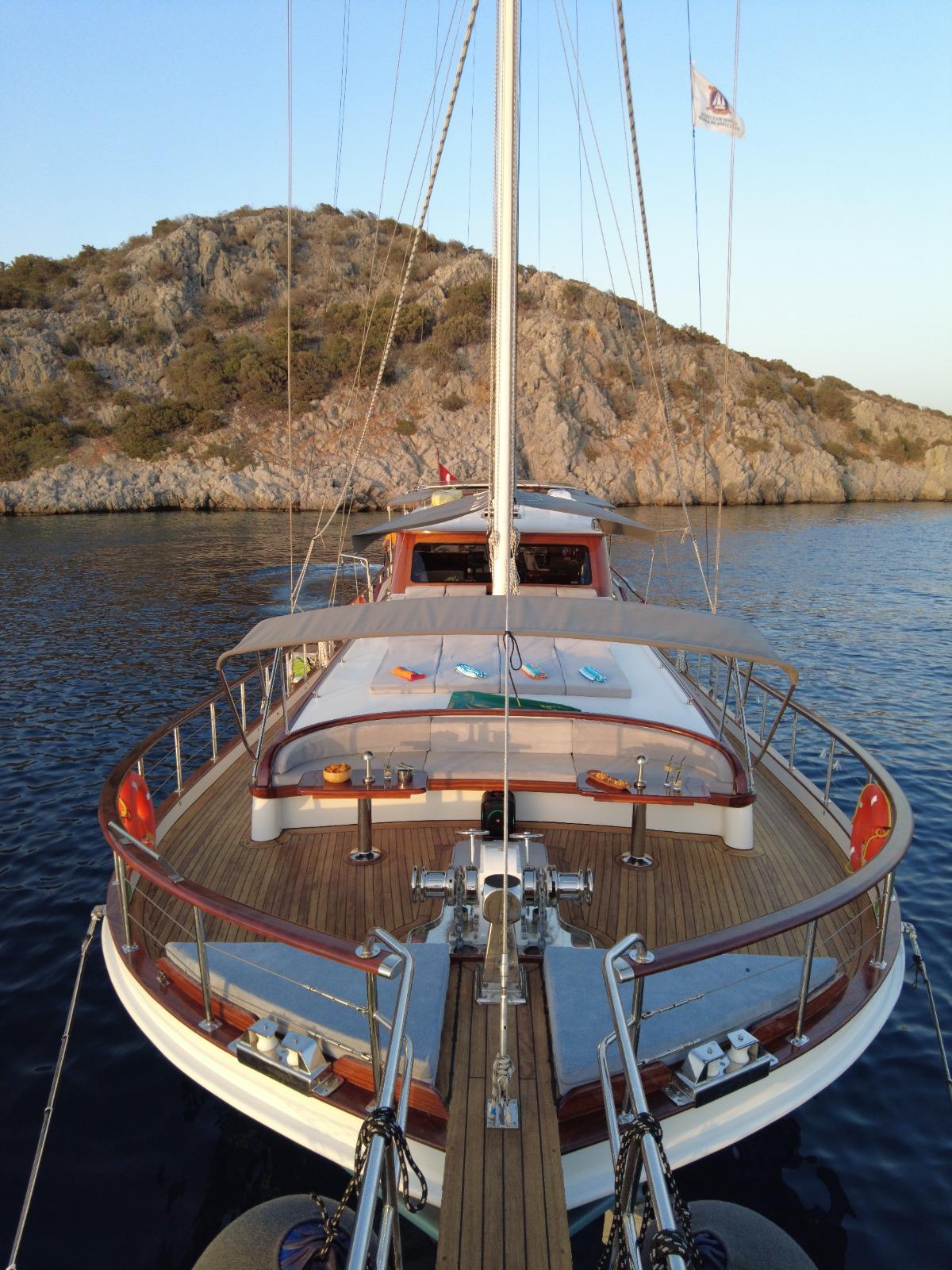 gulet stern deck with curved seating area and dining table anchored in Mediterranean bay