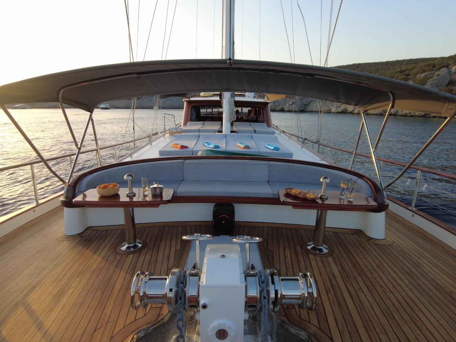 gulet aft deck with curved seating, helm station, and teak decking at sunset